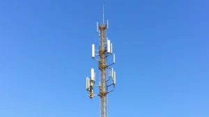 Modern wireless communication tower with multiple antennas against blue sky, professional telecommunications infrastructure photography, daylight outdoor setting